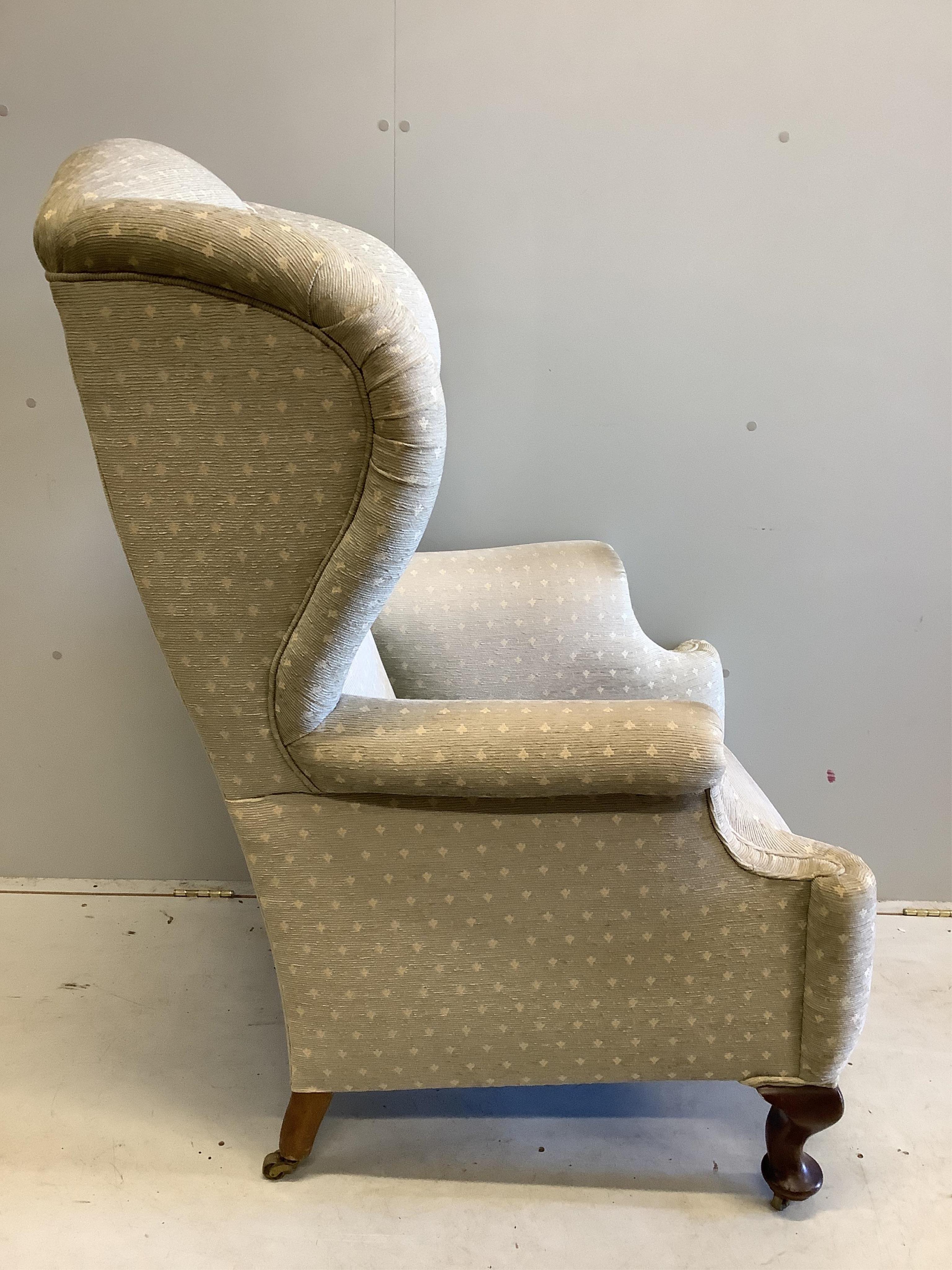 An early 20th century upholstered wing armchair, width 80cm, depth 80cm, height 124cm. Condition - fair